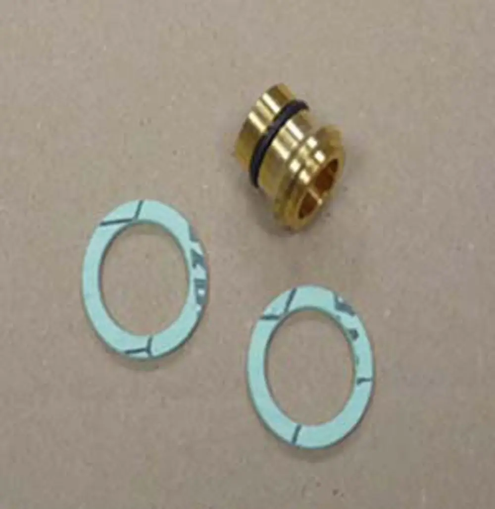 Remeha Komponenten für einen Flüssiggasumstellsatz, bestehend aus einem goldenen Anschlussstück und zwei blauen Dichtungen, auf einer neutralen Unterlage.